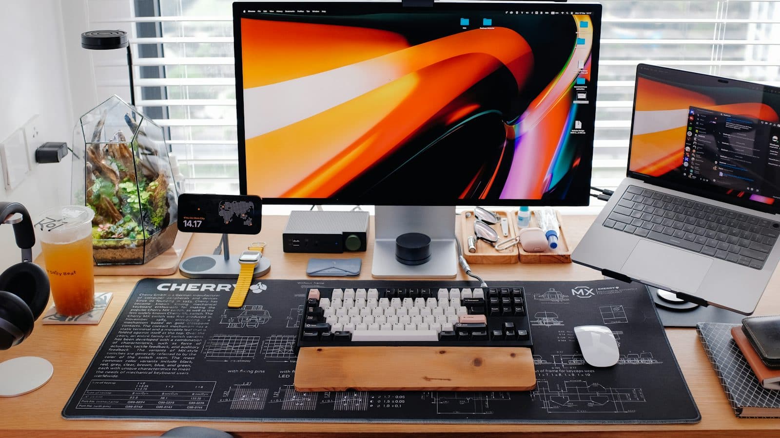 A desk running a monitor, a laptop, a tablet stand, a smartwatch and headphones side by side