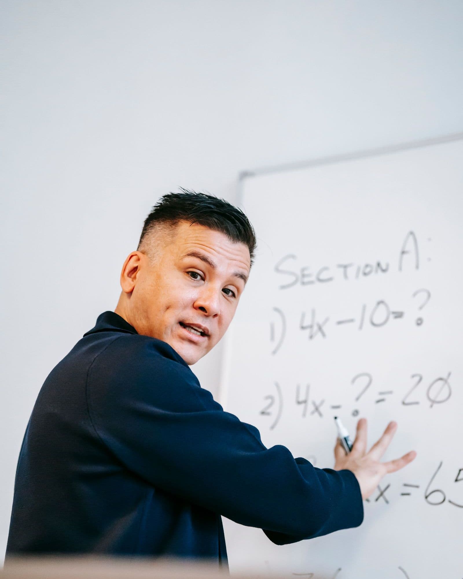 An instructor working through a problem at a whiteboard